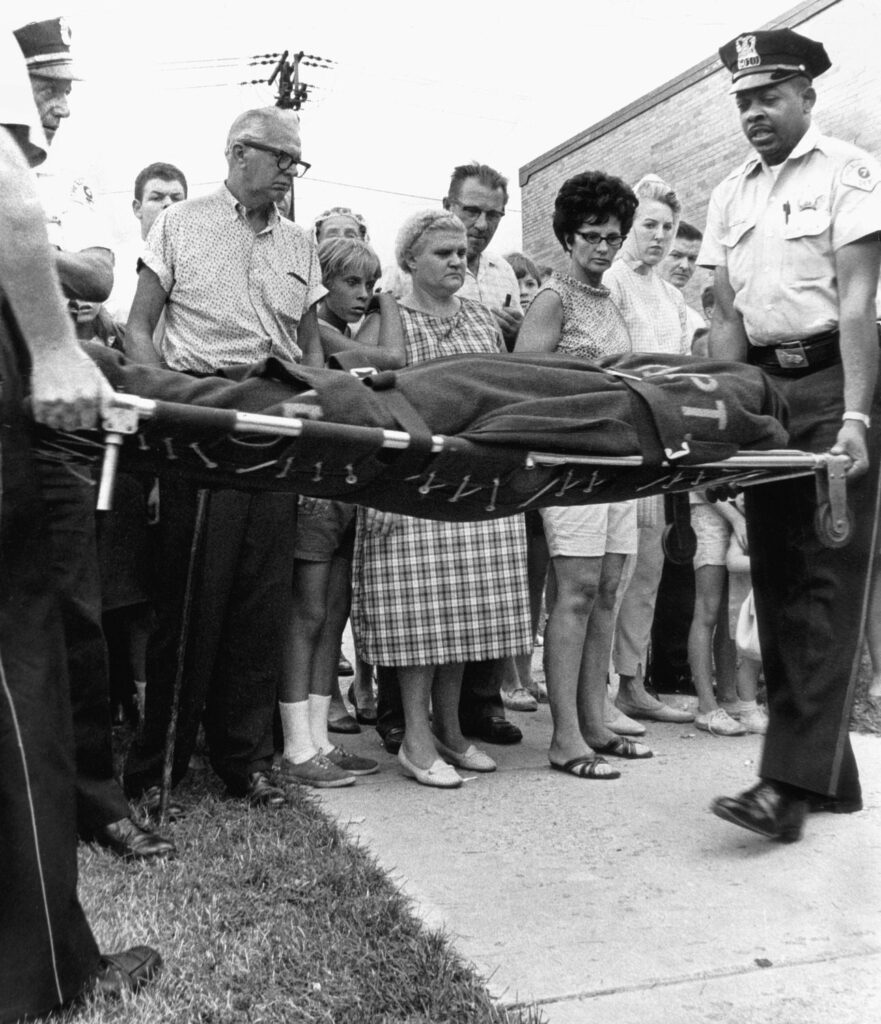 Uteliaat naapurit seuraavat, kun poliisi kuljettaa kahdeksan opiskelijaa ulos asuntolasta 14. heinäkuuta 1966.